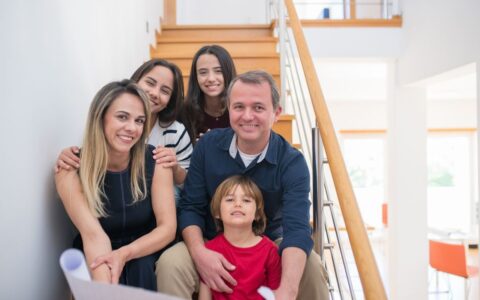 A cheerful family of five sitting together on an indoor staircase, enjoying quality time.