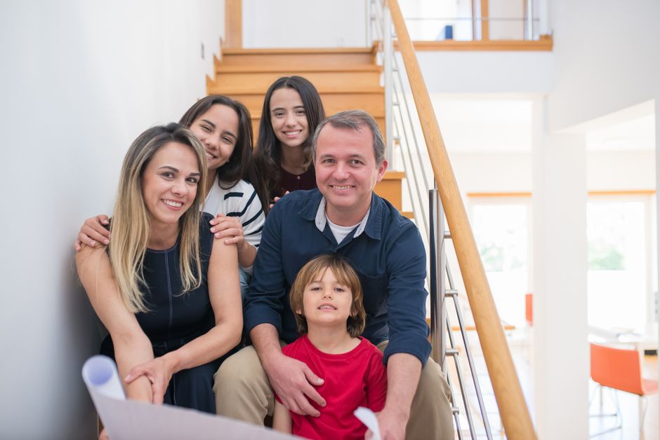A cheerful family of five sitting together on an indoor staircase, enjoying quality time.