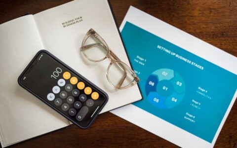 Open notebook, smartphone, and eyeglasses on a desk for business planning.