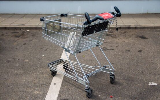 Empty metal shopping cart in a parking lot, positioned on a marked line.