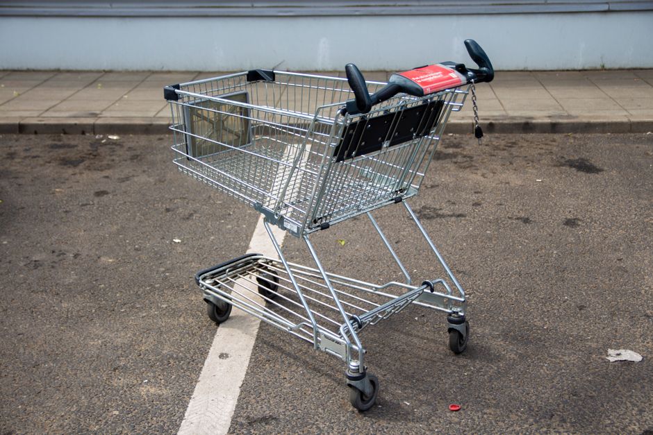 Empty metal shopping cart in a parking lot, positioned on a marked line.