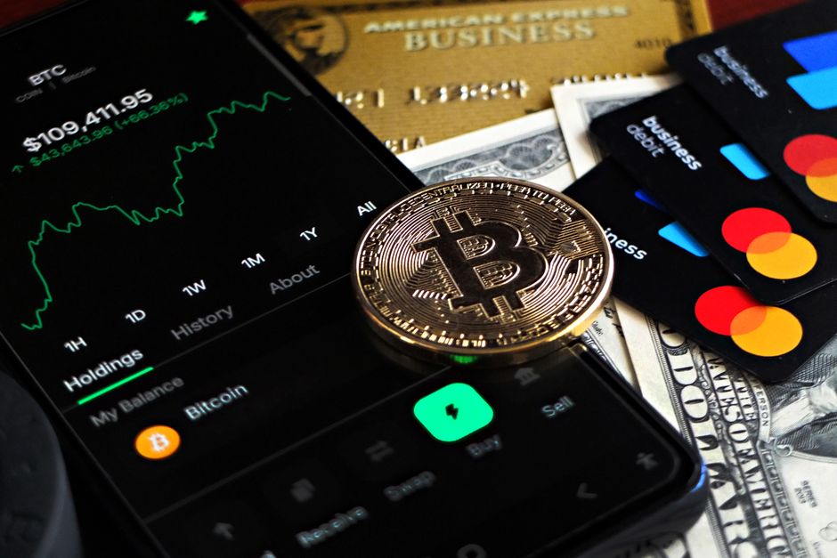 Bitcoin coin with financial data, credit cards, and currency on a desk.