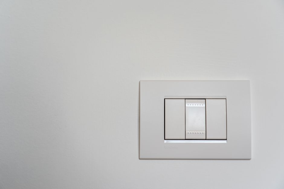 Close-up of a modern white light switch on a clean wall.