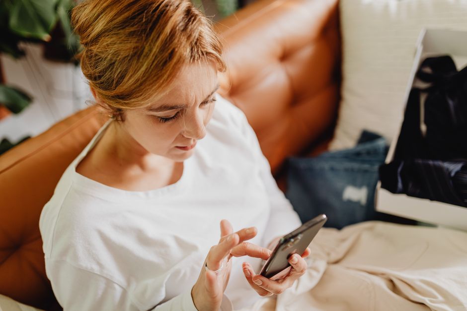 Woman sitting on a sofa using a smartphone at home.