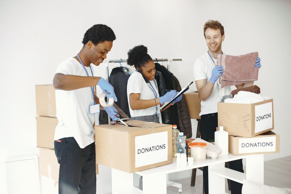 Diverse volunteers happily sorting donation boxes indoors during a charity event.