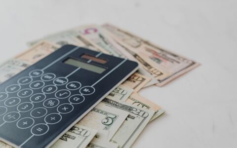 A close-up of a calculator and US dollar banknotes, symbolizing financial calculation and budgeting.