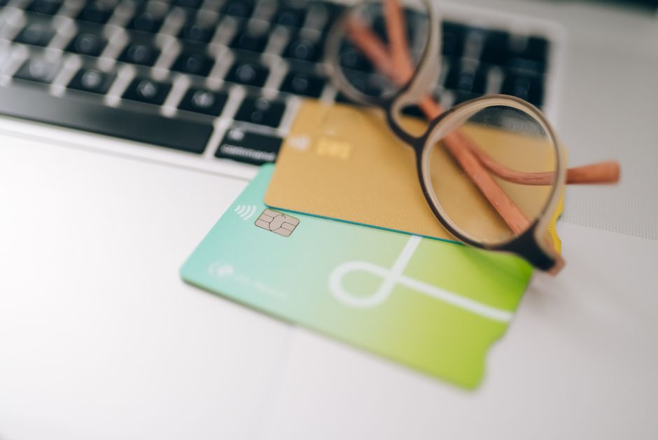 Close-up of eyeglasses and credit cards on a laptop, emphasizing finance and technology.